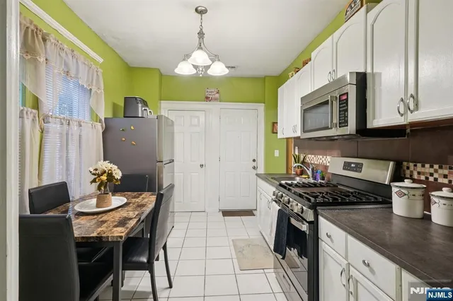 a kitchen with stainless steel appliances granite countertop a stove a refrigerator a kitchen island a dining table and chairs with wooden floor