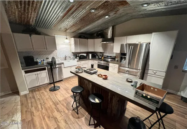 a kitchen with stainless steel appliances a sink a stove a refrigerator cabinets and wooden floor