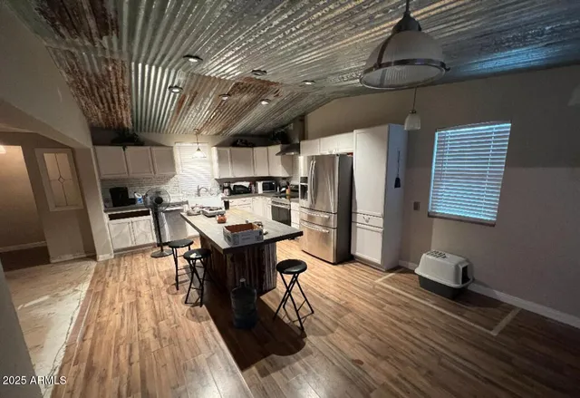 a kitchen with stainless steel appliances a stove a refrigerator a sink dishwasher and a dining table with wooden floor