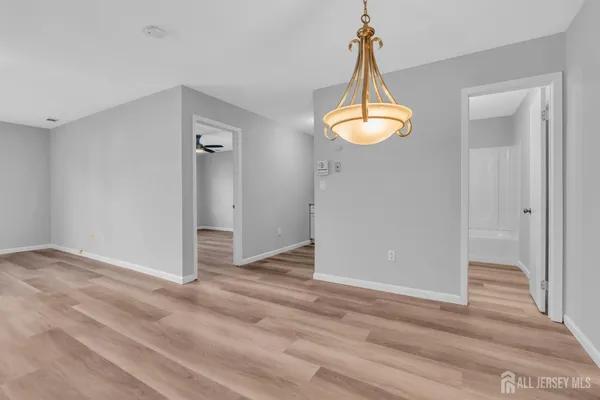 an empty room with wooden floor windows and a chandelier
