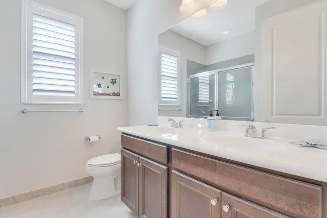 a bathroom with a granite countertop sink a toilet and a window