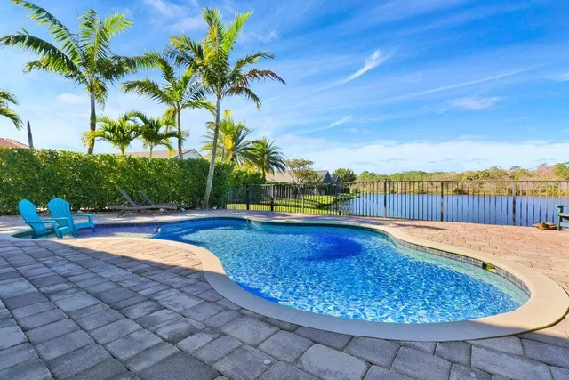 a view of a swimming pool with a lounge chair and trees in the background