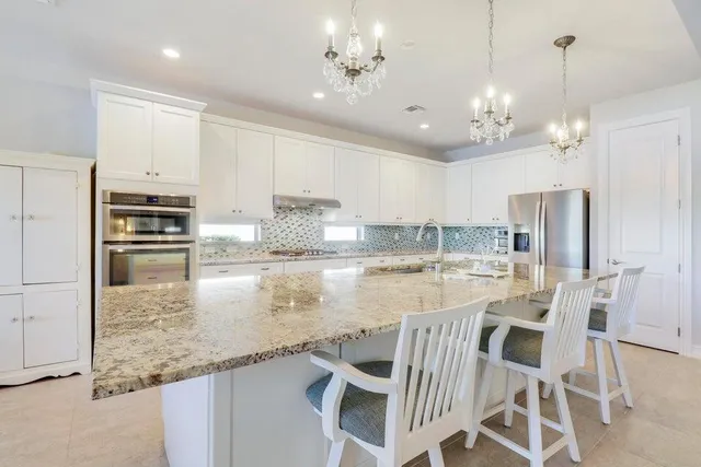 a kitchen with kitchen island granite countertop a white cabinets and stainless steel appliances