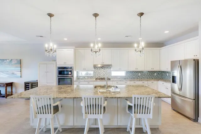 a kitchen with kitchen island a dining table chairs stainless steel appliances and cabinets