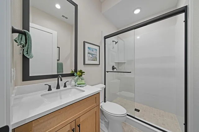 a bathroom with a shower sink vanity mirror and toilet