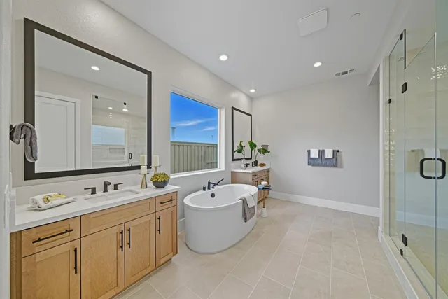 a spacious bathroom with a double vanity sink a mirror and a bathtub