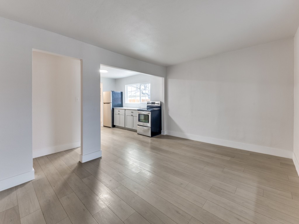 1108 Vasquez Street Austin, TX 78741 - Photo 13 of 33 a view of a kitchen and an empty room with wooden floor and kitchen