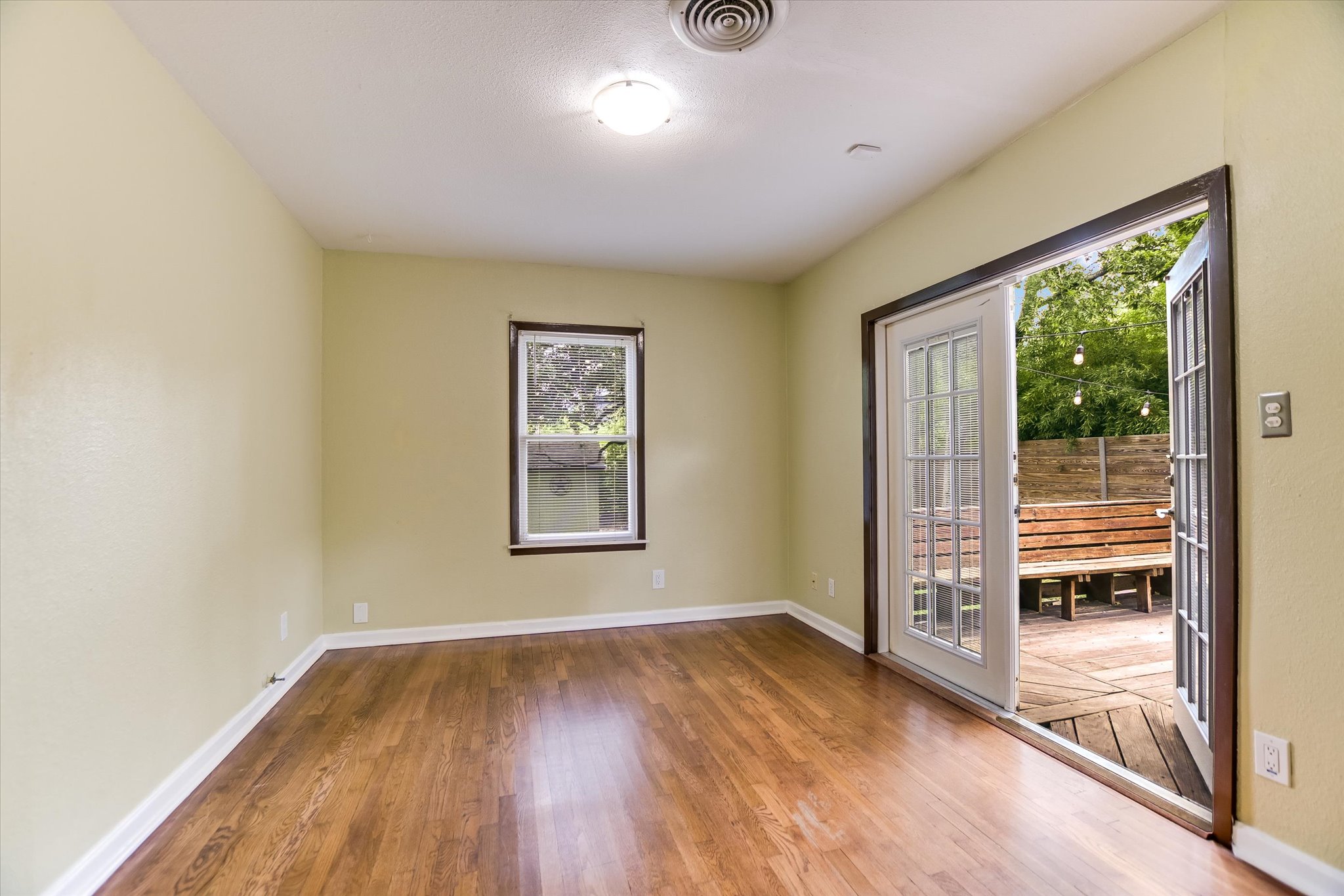 208 Braeswood Road Austin, TX 78704 - Photo 13 of 20 Hardwood floors stretch towards the glass French doors, opening to a private wooden deck.