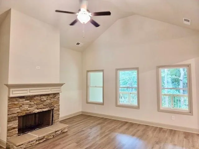 a view of an empty room with wooden floor fireplace and a window