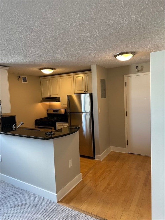 a kitchen with stainless steel appliances granite countertop a refrigerator a stove and a sink with wooden floor