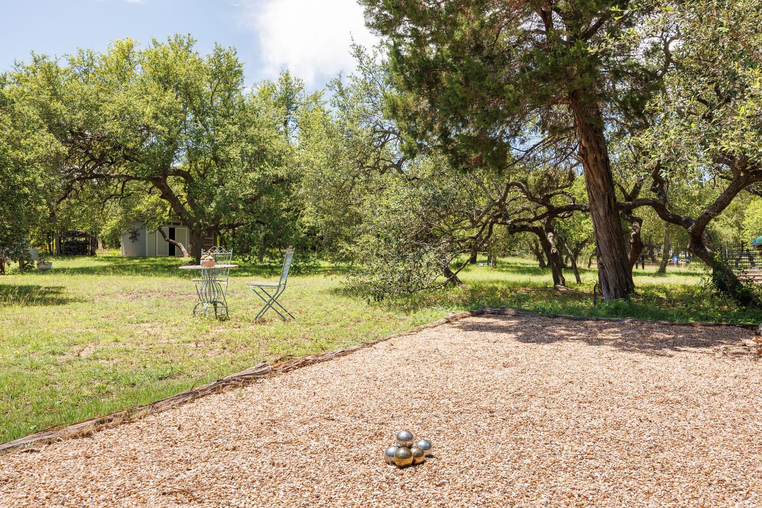 1135 Blue Ridge Drive Dripping Springs, TX 78620 - Photo 32 of 36 A tranquil outdoor area for relaxation or games, nestled among mature trees and a manicured lawn.
