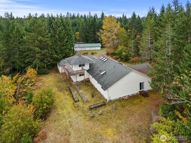 aerial view of a house with yard and trees in the background