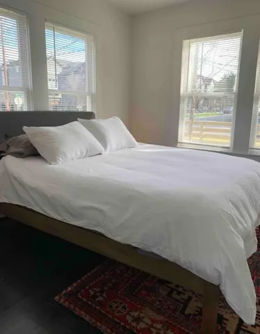 a bedroom with a bed wooden floor and window