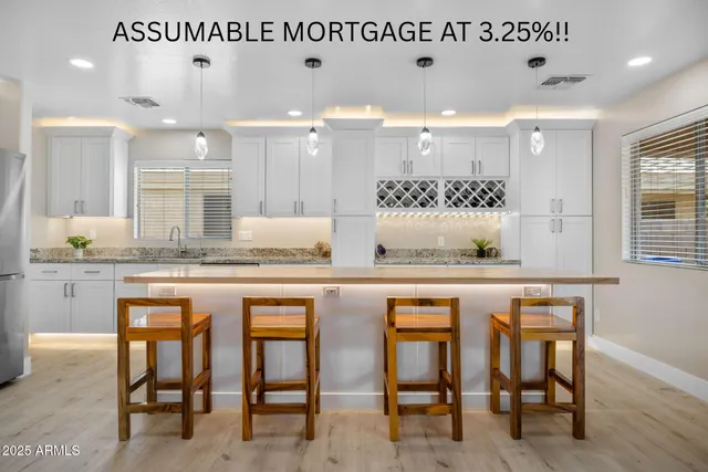 a dining hall with stainless steel appliances granite countertop a table chairs sink and wooden cabinets