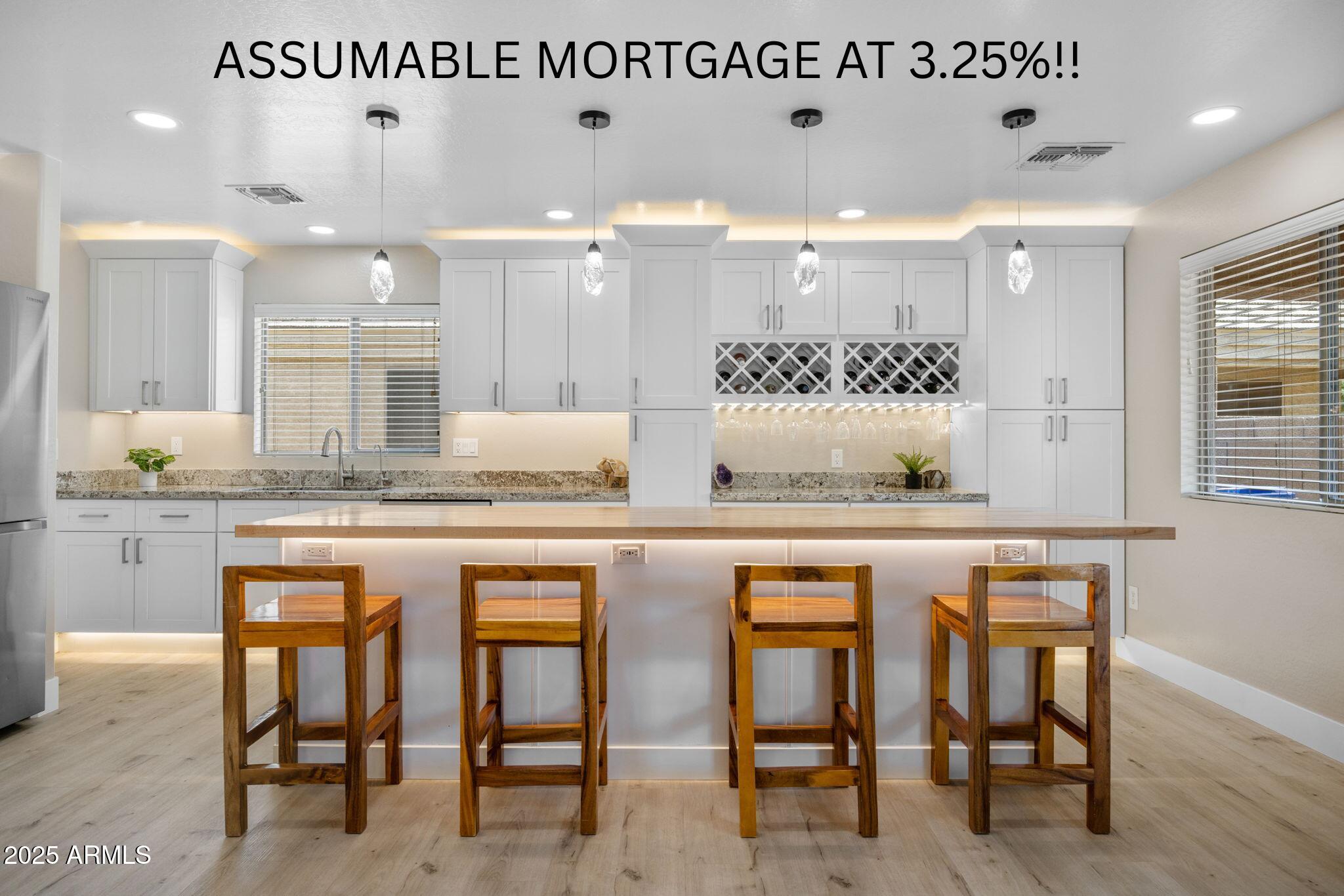 a dining hall with stainless steel appliances granite countertop a table chairs sink and wooden cabinets