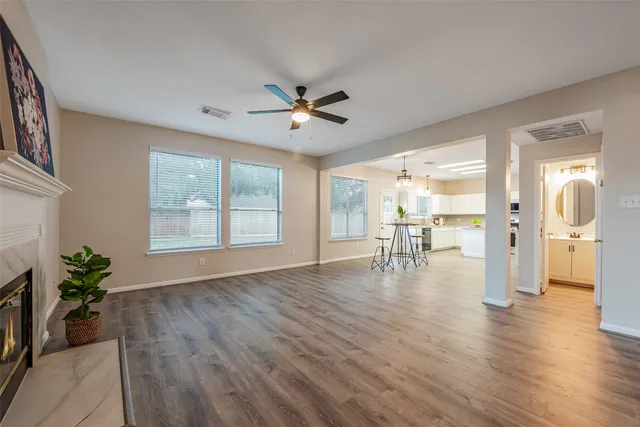 a view of an empty room with wooden floor a fireplace and a window