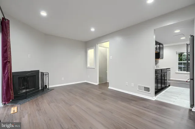 a view of an empty room with wooden floor and a fireplace