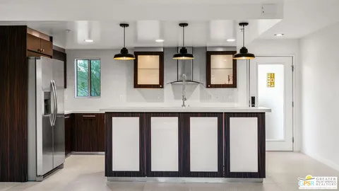 a kitchen with stainless steel appliances kitchen island granite countertop a refrigerator a sink and white cabinets