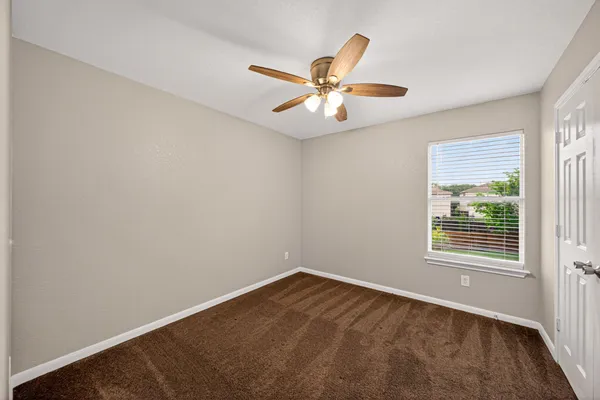 an empty room with a window and a fan