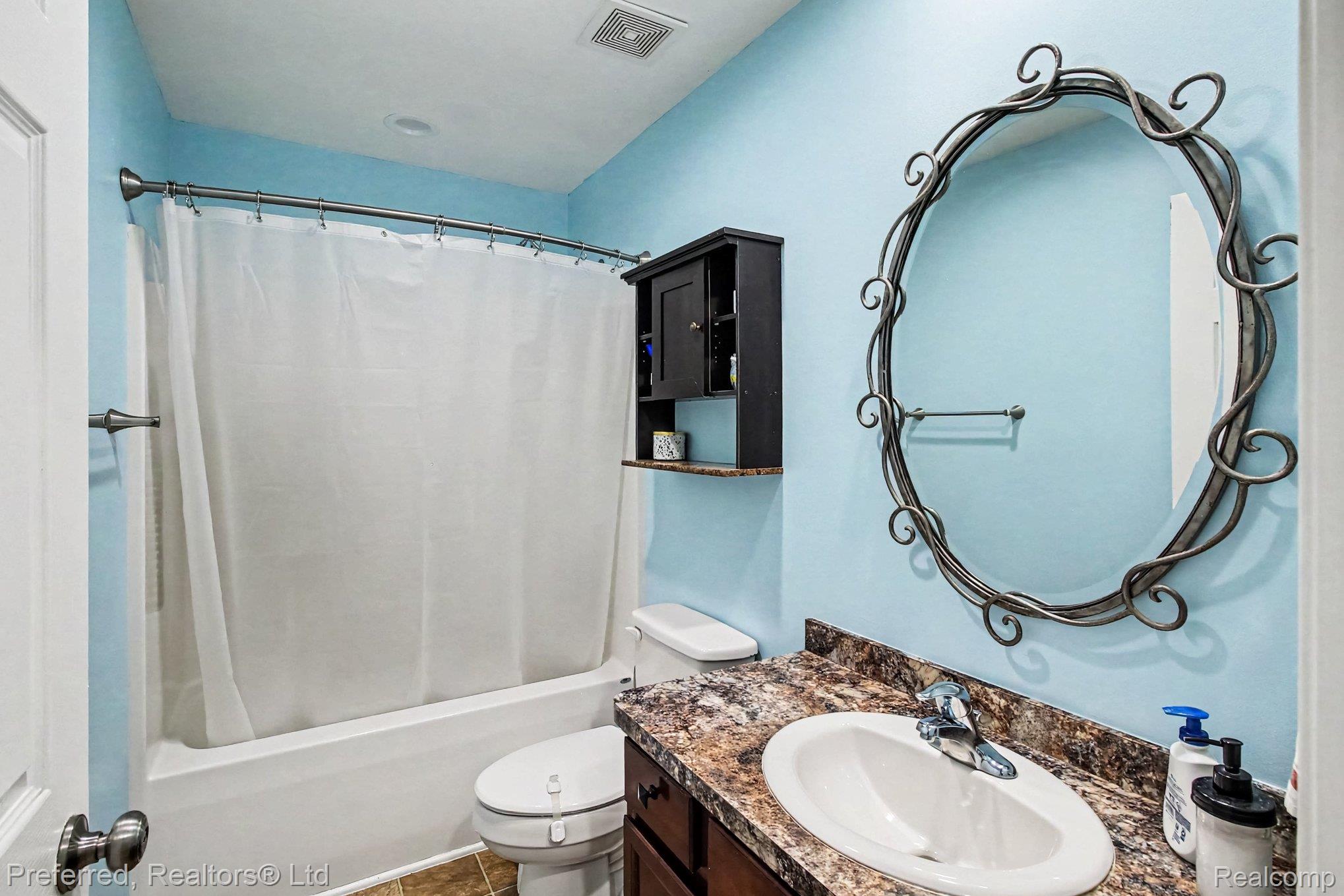 6366 Dutcher Road Howell, MI 48843 - Photo 23 of 33 Bathroom featuring a curved shower rod, built-in shelving, dark wood vanity with an integrated sink, and an ornate framed mirror