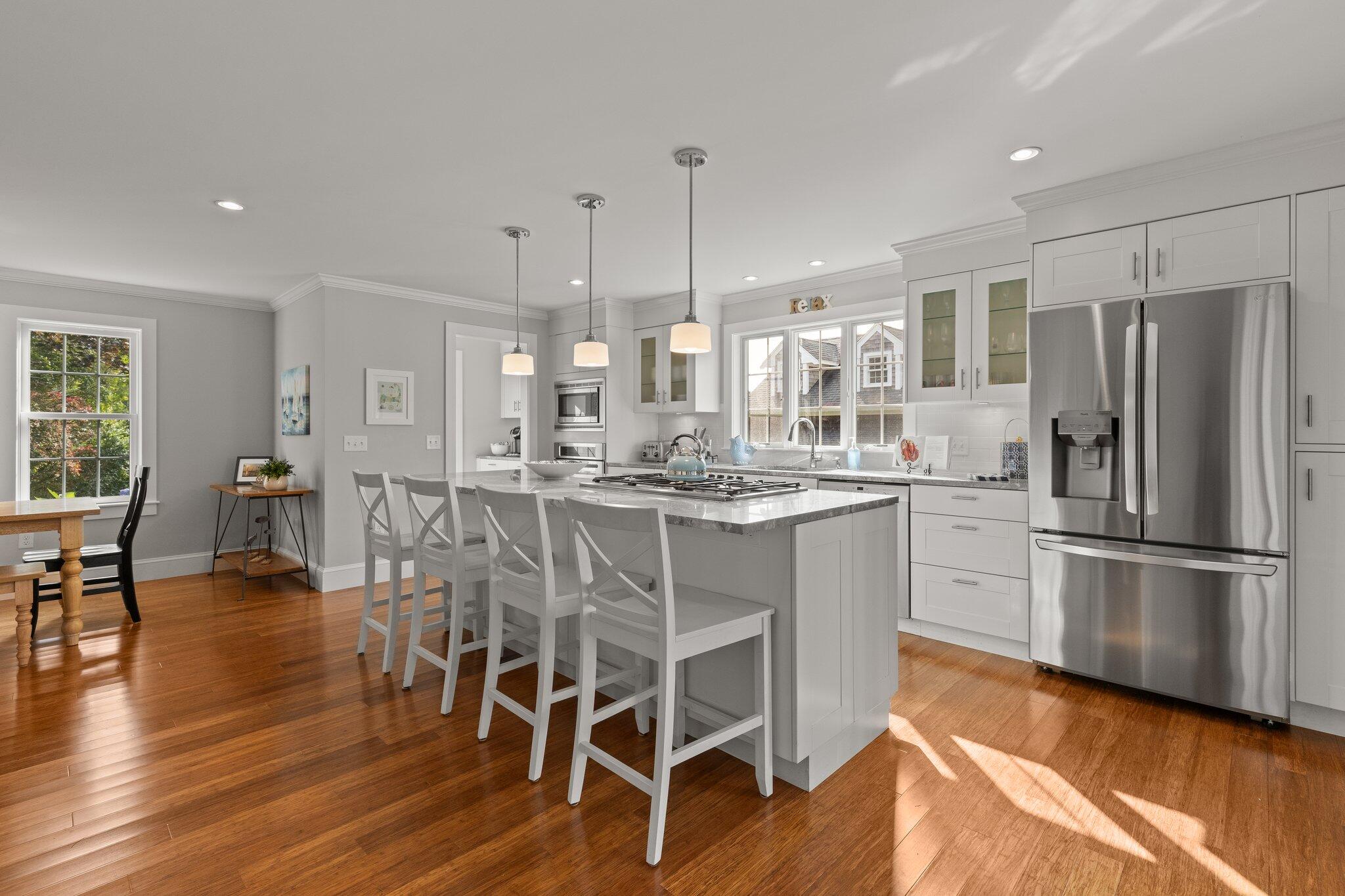 96 Pochet Road Orleans, MA 02653 - Photo 19 of 55 a kitchen with stainless steel appliances kitchen island granite countertop a refrigerator a stove a dining table and chairs with wooden floor
