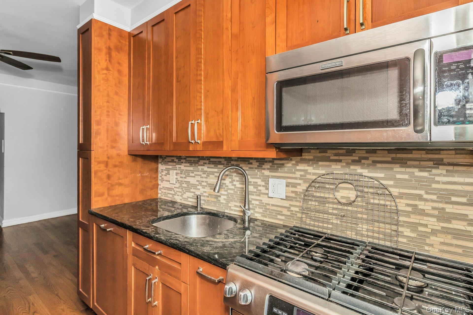 111-39 76th Road, Unit B7 Queens, NY 11375 - Photo 11 of 16 Kitchen with stainless steel appliances, tasteful backsplash, dark stone countertops, dark wood-style floors, and brown cabinetry
