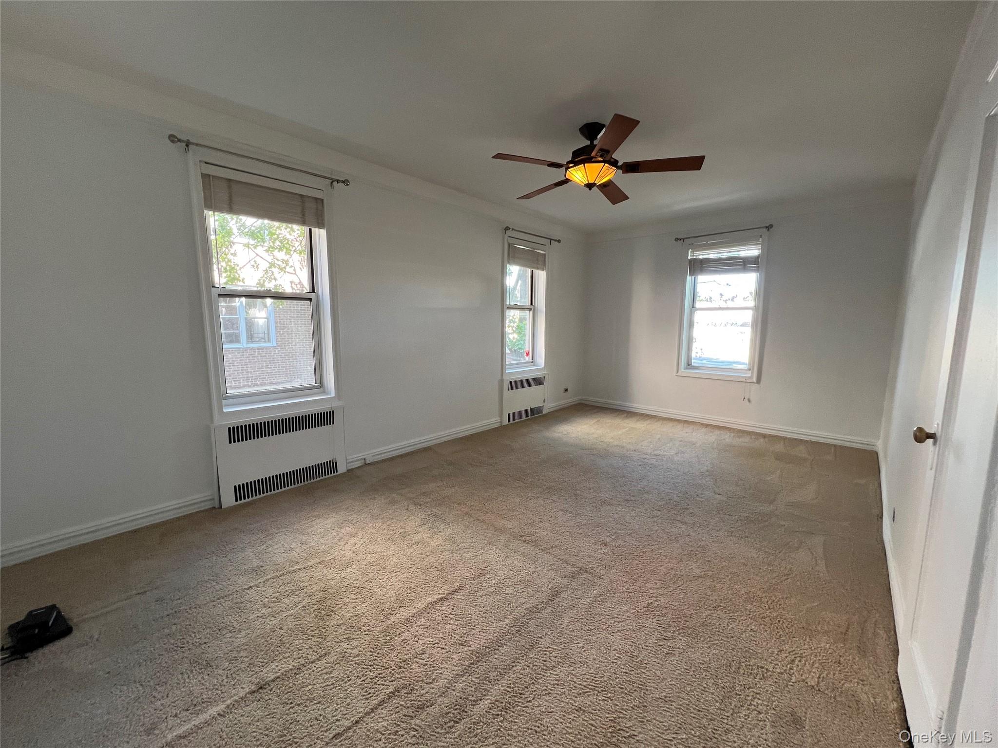 111-39 76th Road, Unit B7 Queens, NY 11375 - Photo 12 of 16 Unfurnished room with radiator heating unit, carpet, ceiling fan, and crown molding