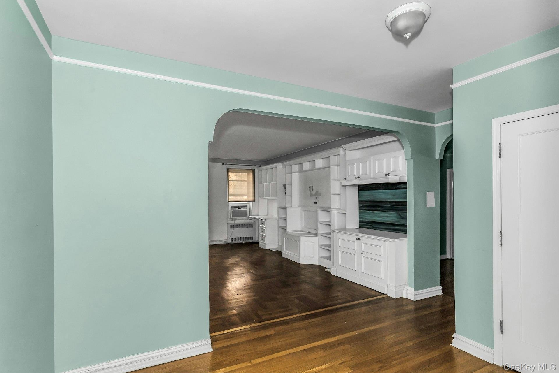 111-39 76th Road, Unit B7 Queens, NY 11375 - Photo 3 of 16 Unfurnished living room featuring arched walkways and dark wood finished floors