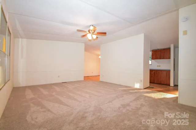 an empty room with windows chandelier fan and windows