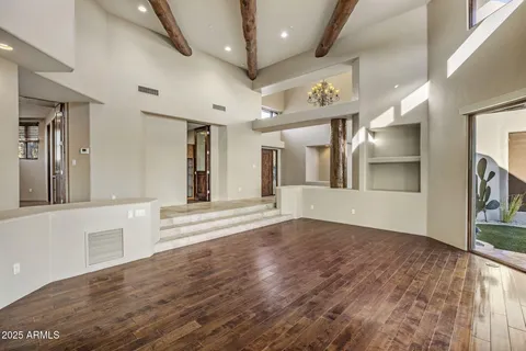 a view of an empty room with wooden floor fireplace and a window