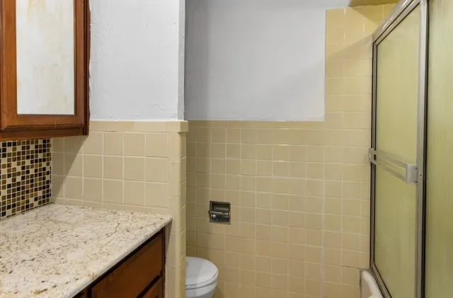 a bathroom with a granite countertop sink toilet and mirror