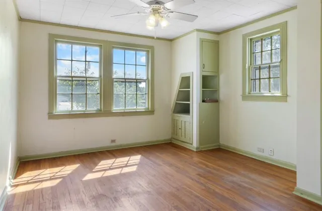 an empty room with wooden floor and windows