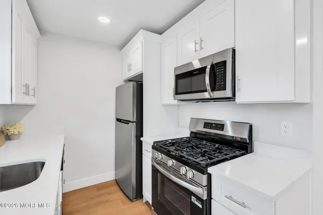 a kitchen with stainless steel appliances kitchen island granite countertop a sink a stove a microwave and refrigerator