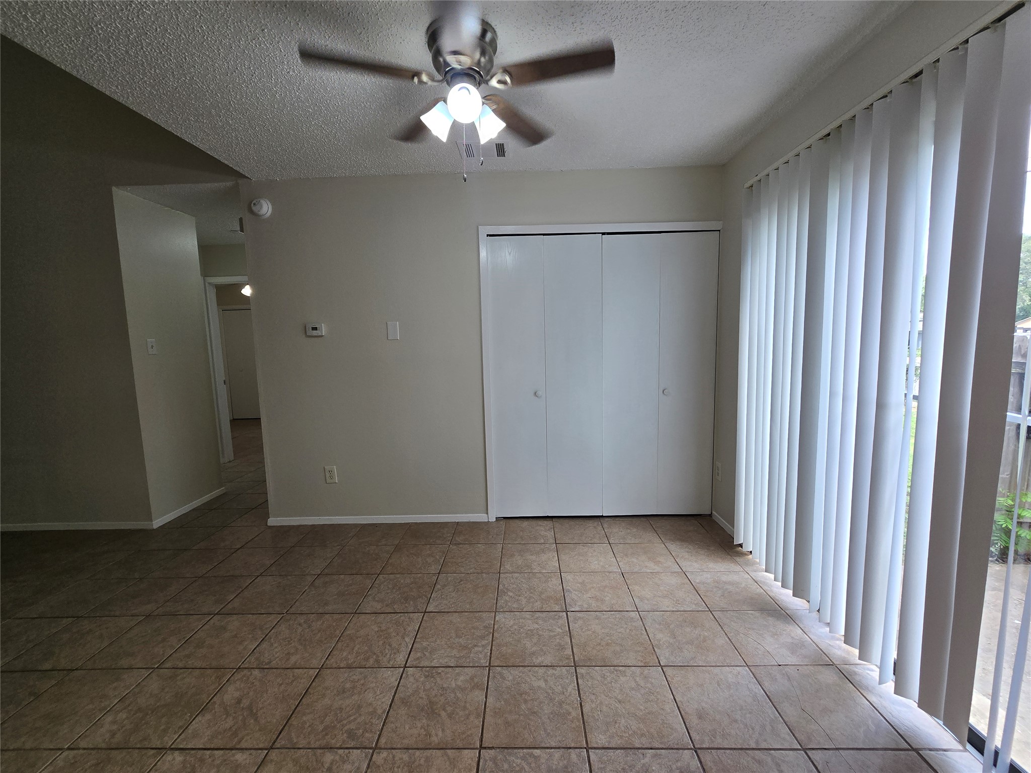 6206 Buffalo Pass, Unit A Austin, TX 78745 - Photo 8 of 24 A living space offers tiled flooring, a ceiling fan, and sliding doors to the exterior.