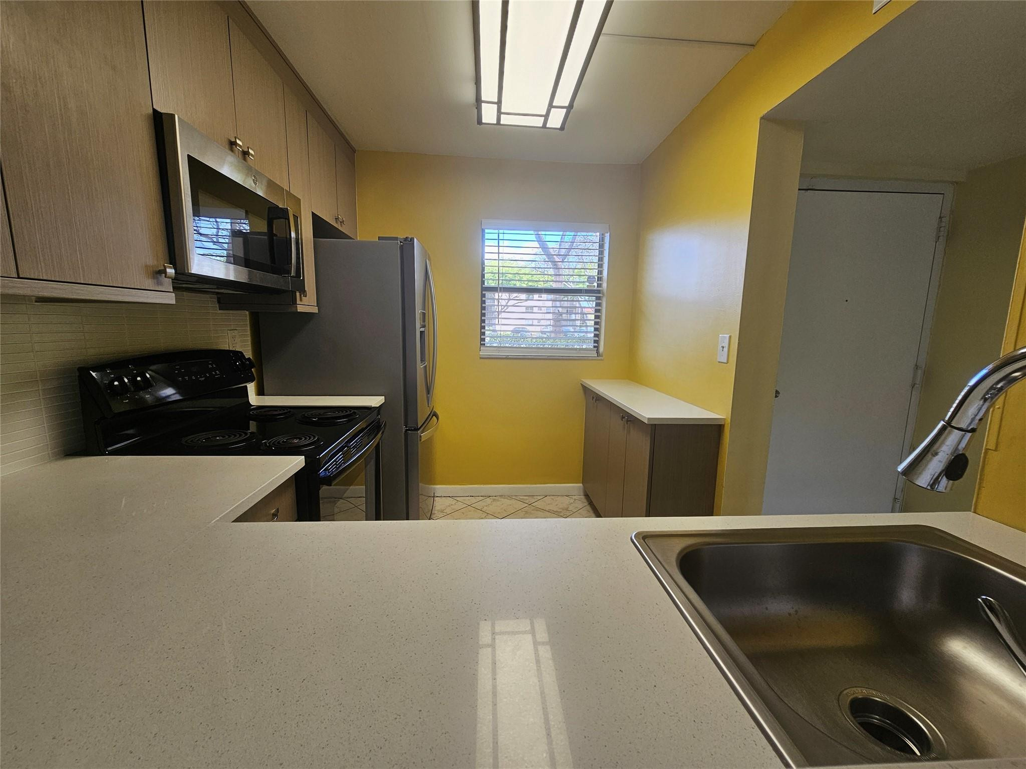 3396 Foxcroft Road, Unit 110 Miramar, FL 33025 - Photo 9 of 24 a kitchen with stainless steel appliances a stove a microwave a sink and a refrigerator