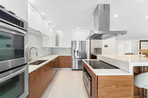 a large kitchen with stainless steel appliances a sink a stove and a refrigerator