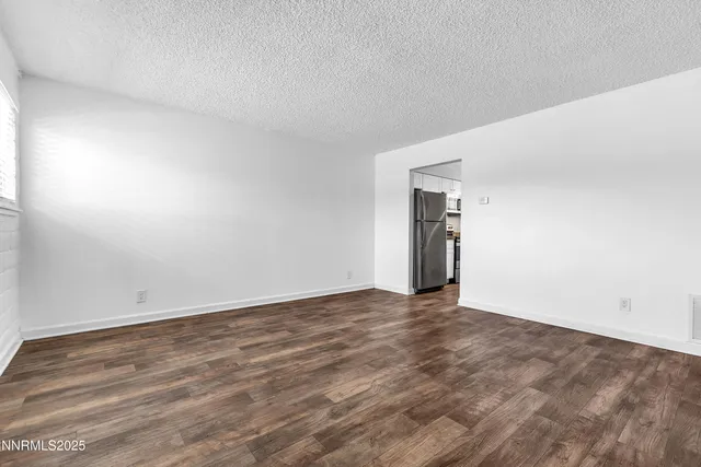 a view of an empty room with wooden floor and closet