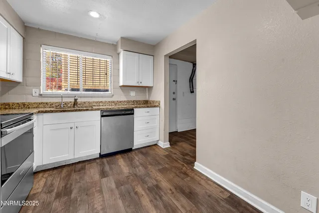 a kitchen with stainless steel appliances granite countertop a stove a sink and white cabinets with wooden floor