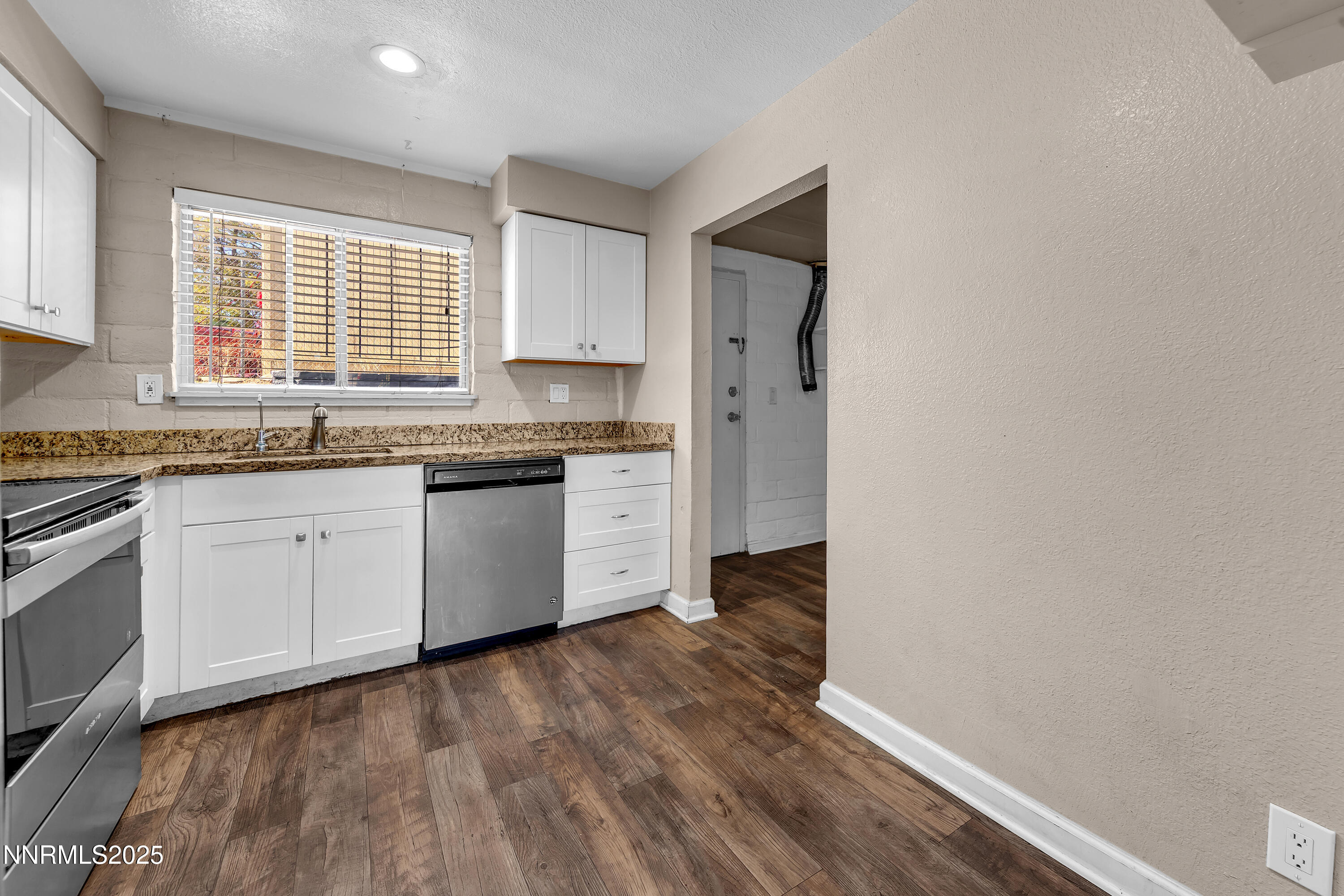 1436 East 9th Street, Unit 8 Reno, NV 89512 - Photo 8 of 19 a kitchen with stainless steel appliances granite countertop a stove a sink and white cabinets with wooden floor