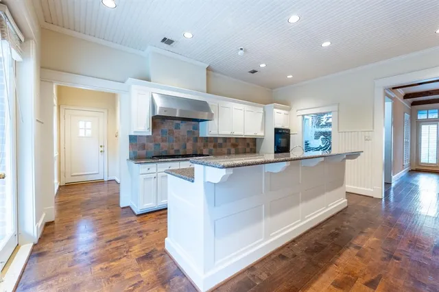 a large white kitchen with stainless steel appliances granite countertop a stove a sink and a large window