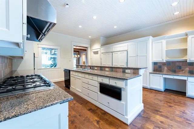 a large kitchen with granite countertop a large counter top and stainless steel appliances