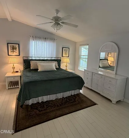 a bedroom with a bed a mirror on dresser and a window