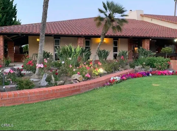 a view of a house with a big yard and potted plants
