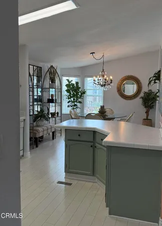 a kitchen with a sink dishwasher a dining table and chairs with wooden floor