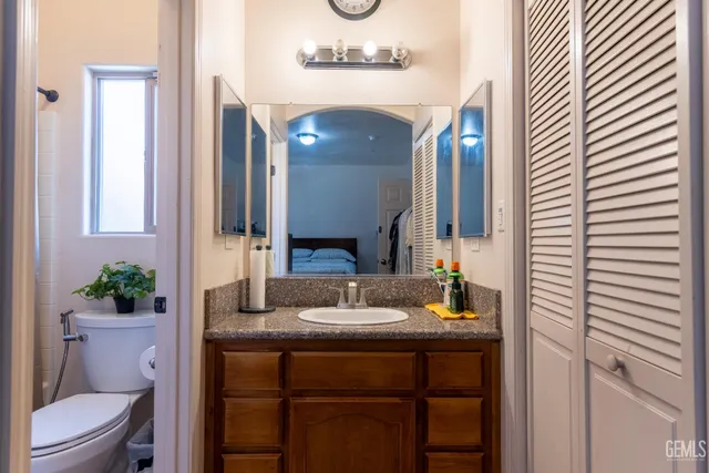 a bathroom with a granite countertop sink and a mirror with toilet