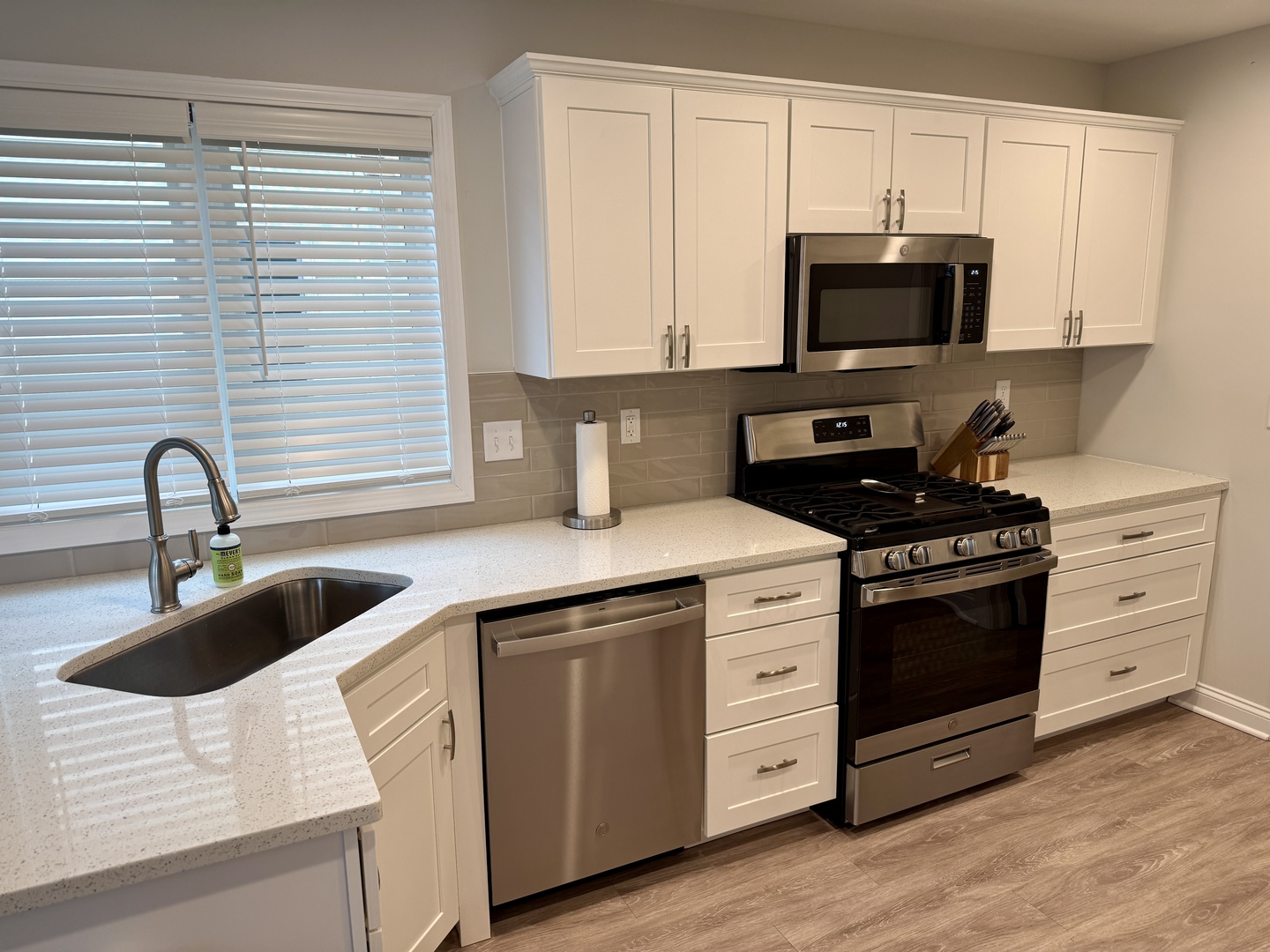 2222 Maggie Lane Sycamore, IL 60178 - Photo 9 of 24 a kitchen with white cabinets a sink and a stove with wooden floor