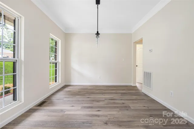 a view of an empty room with window and wooden floor