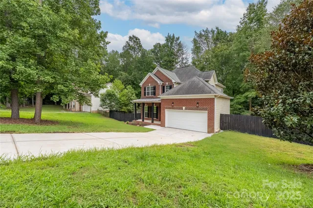 a view of a house with a big yard and large trees