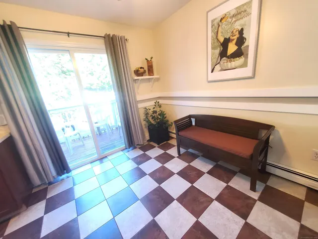 a living room with a black white checkered floor with a gaming machine and dining chair