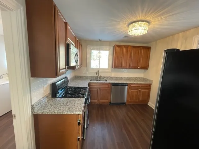 a kitchen with granite countertop a sink cabinets and wooden floor
